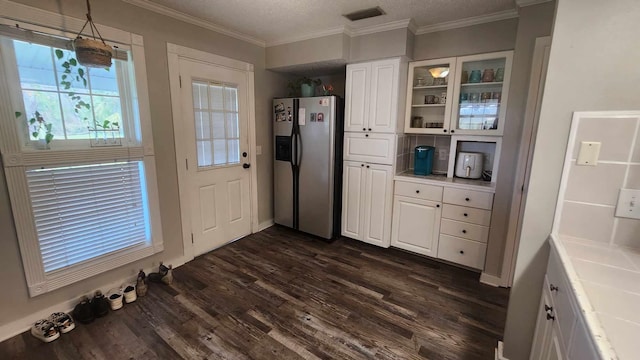 kitchen with visible vents, dark wood finished floors, ornamental molding, stainless steel refrigerator with ice dispenser, and white cabinetry