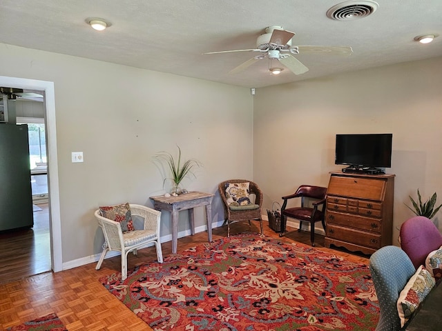 living area featuring a textured ceiling, ceiling fan, and parquet flooring