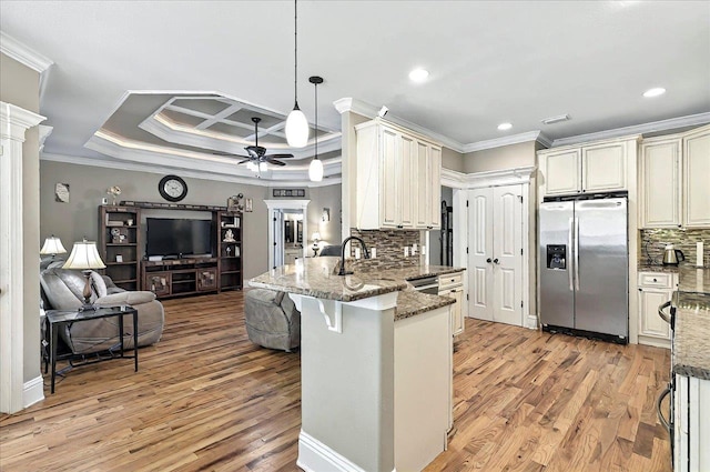 kitchen with open floor plan, a peninsula, ornamental molding, and stainless steel fridge with ice dispenser