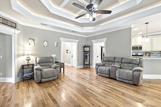 living room with visible vents, light wood-style flooring, ceiling fan, and crown molding