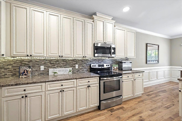 kitchen with backsplash, crown molding, appliances with stainless steel finishes, and light wood finished floors
