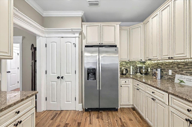 kitchen featuring light wood-type flooring, visible vents, ornamental molding, stone countertops, and stainless steel fridge with ice dispenser