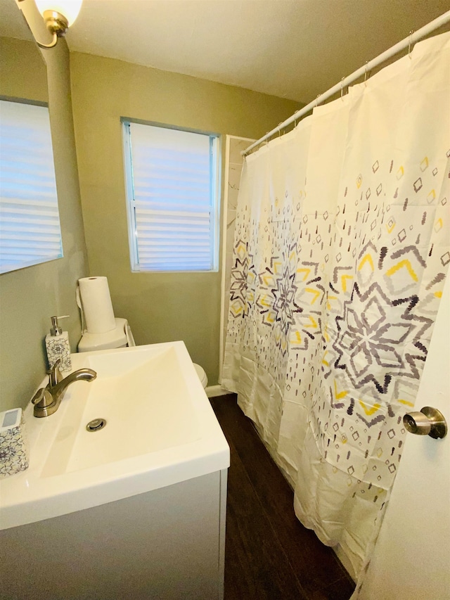 bathroom featuring toilet, vanity, wood-type flooring, and walk in shower