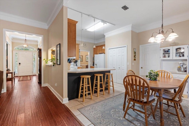 dining space with ornamental molding, light hardwood / wood-style flooring, rail lighting, and a chandelier