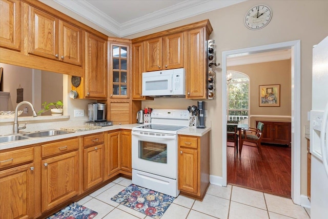 kitchen with crown molding, sink, white appliances, and light tile patterned floors