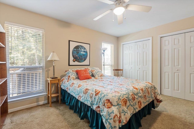 bedroom with multiple closets, light colored carpet, and ceiling fan