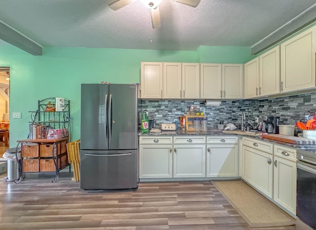 kitchen featuring decorative backsplash, appliances with stainless steel finishes, light hardwood / wood-style floors, and ceiling fan