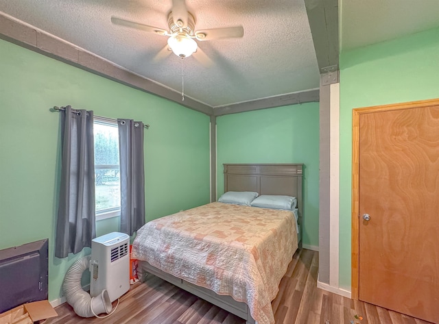 bedroom with a textured ceiling, hardwood / wood-style flooring, and ceiling fan