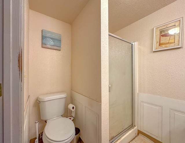 bathroom featuring a shower with door and toilet