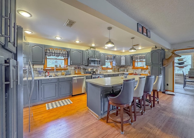 kitchen with stainless steel appliances, decorative backsplash, light hardwood / wood-style flooring, and a kitchen island