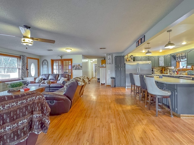 living room featuring ceiling fan, a textured ceiling, and light wood-type flooring