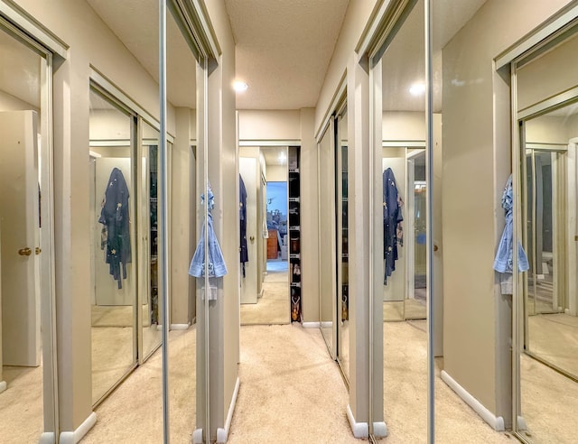 hall with light carpet and a textured ceiling