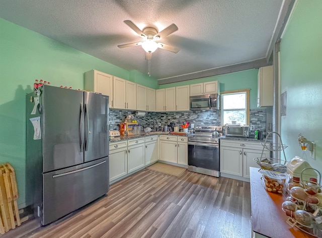 kitchen featuring a textured ceiling, appliances with stainless steel finishes, ceiling fan, and light hardwood / wood-style flooring