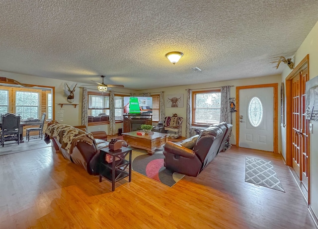 living room with a textured ceiling, hardwood / wood-style flooring, and ceiling fan