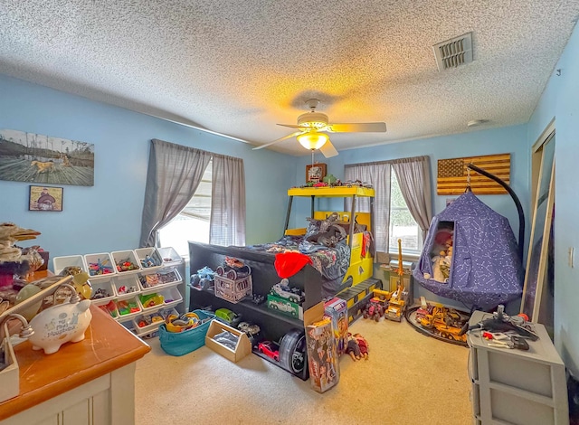 bedroom with a textured ceiling, carpet floors, multiple windows, and ceiling fan