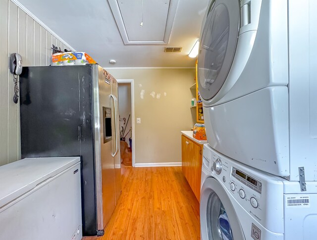 laundry room with light hardwood / wood-style floors, cabinets, crown molding, and stacked washer and clothes dryer