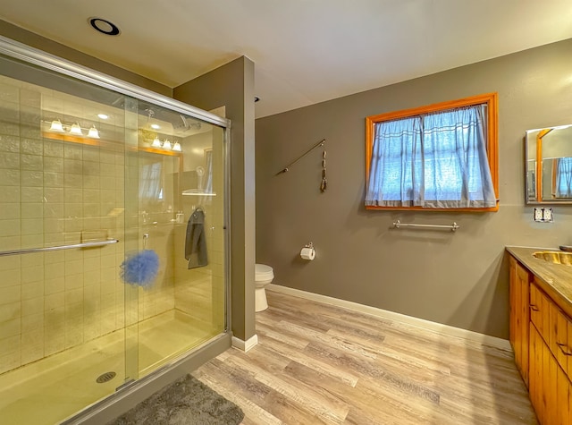 bathroom with a shower with door, wood-type flooring, toilet, and vanity