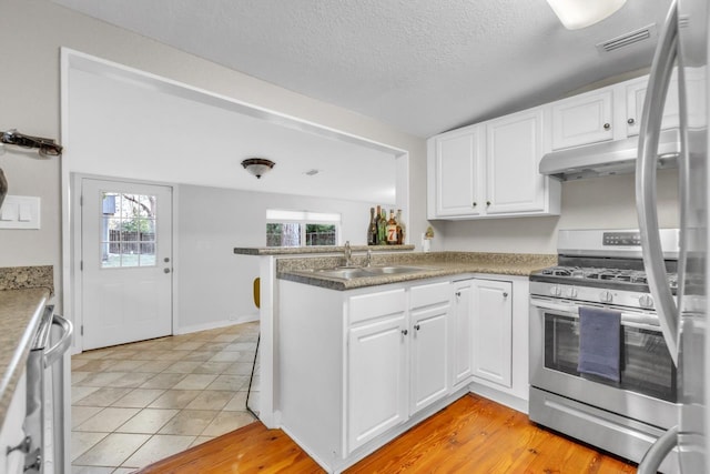 kitchen with sink, white cabinets, kitchen peninsula, gas stove, and a textured ceiling