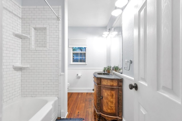 full bathroom featuring vanity, tiled shower / bath, hardwood / wood-style flooring, and toilet