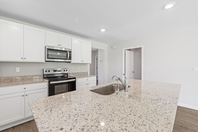 kitchen with white cabinetry, stainless steel appliances, light stone countertops, and sink