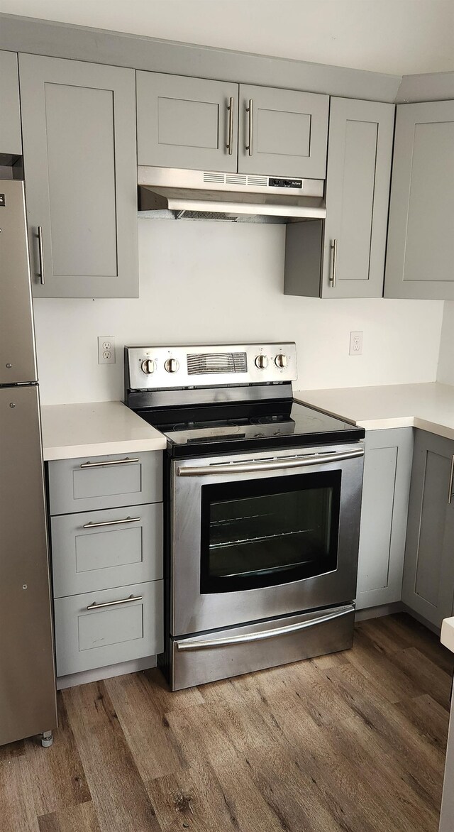 kitchen with stainless steel appliances, ventilation hood, dark wood-type flooring, and gray cabinets