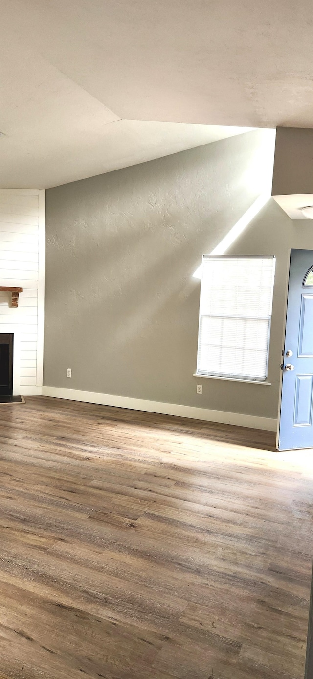 unfurnished living room with hardwood / wood-style floors, vaulted ceiling, and a fireplace