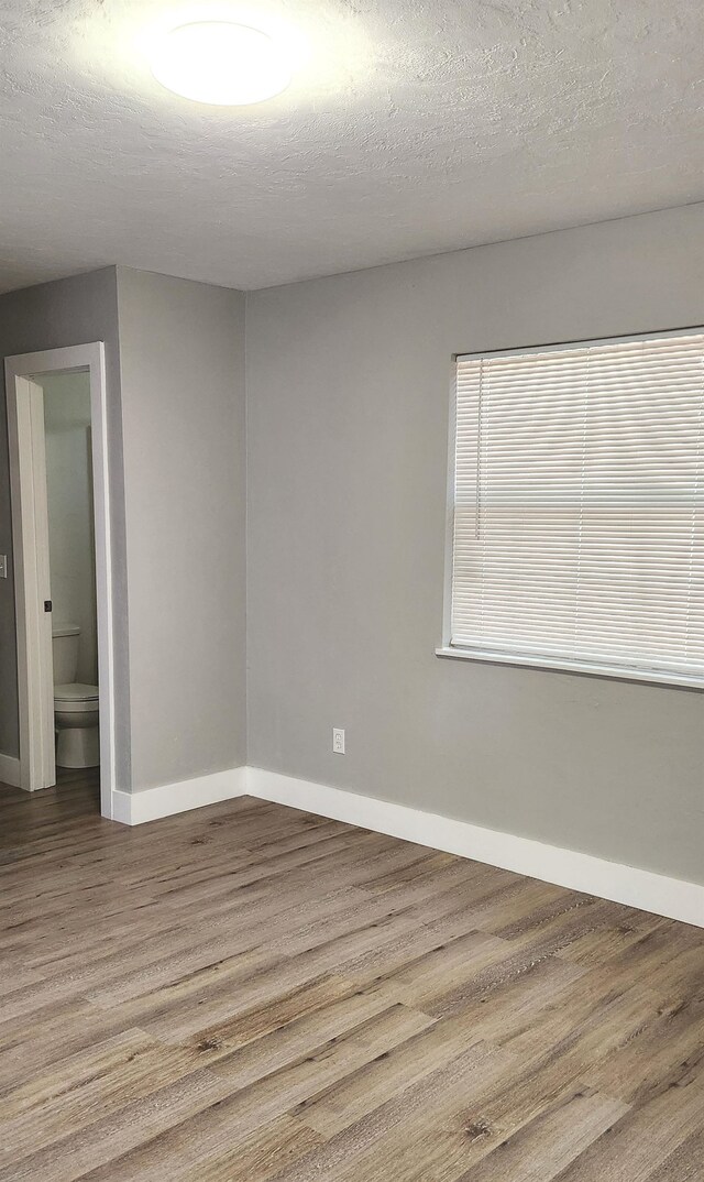 unfurnished room with a textured ceiling and hardwood / wood-style flooring