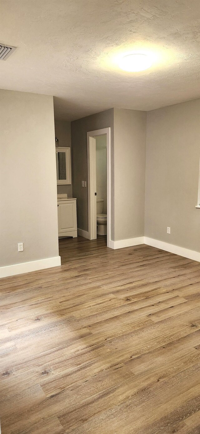 unfurnished room featuring light hardwood / wood-style floors and a textured ceiling