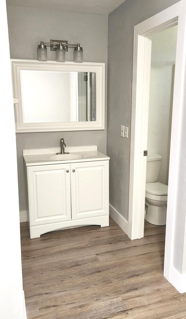 bathroom with wood-type flooring, toilet, and vanity