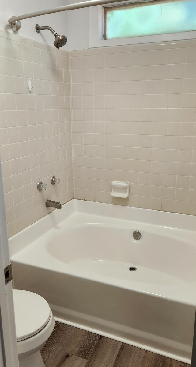 bathroom with toilet, tiled shower / bath, and hardwood / wood-style floors