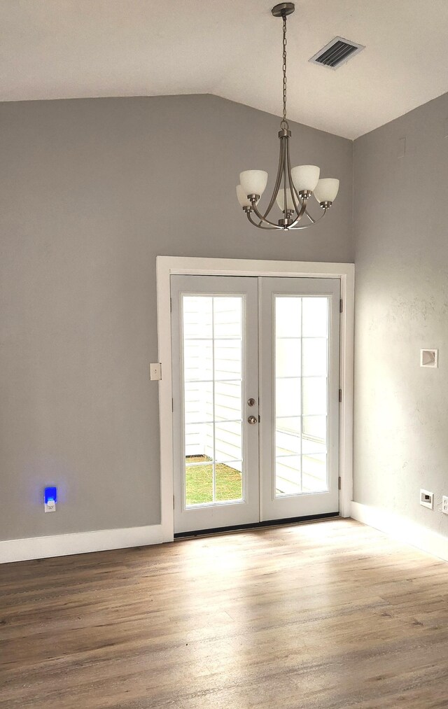 entryway featuring french doors, hardwood / wood-style flooring, a chandelier, and vaulted ceiling