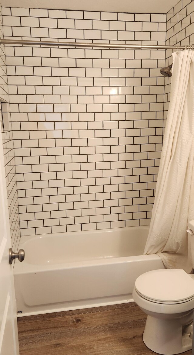 bathroom with shower / bath combo, hardwood / wood-style flooring, and toilet