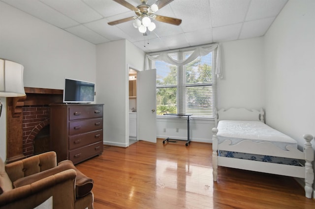 1118 W Green St, Perry, FL 32347 - bedroom featuring light wood finished floors, a drop ceiling, baseboards, a fireplace, and a ceiling fan