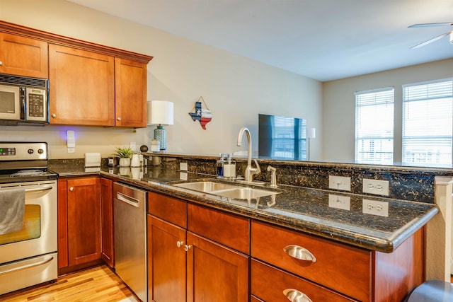 415 Saint Francis St Unit 133, Tallahassee, FL 32301 - kitchen with appliances with stainless steel finishes, a sink, dark stone counters, light wood-style flooring, and a peninsula