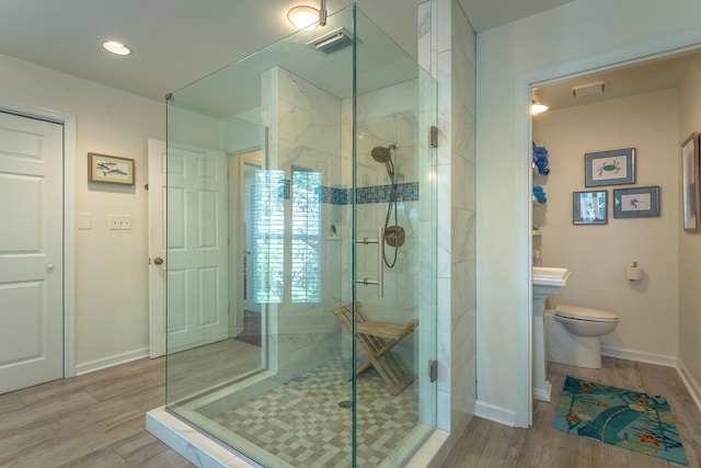 bathroom with hardwood / wood-style flooring, toilet, and walk in shower