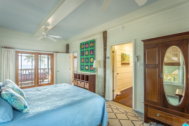 bedroom with beamed ceiling, ceiling fan, and wood walls