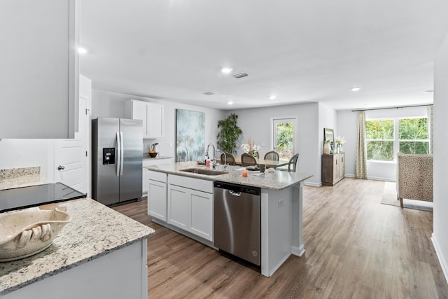 223 Milestone Trl, Crawfordville, FL 32327 - kitchen featuring stainless steel appliances, white cabinets, a center island with sink, light wood-type flooring, and light stone countertops