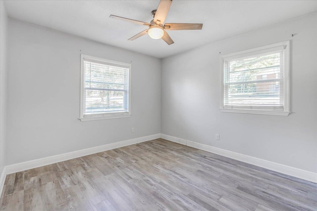 spare room with plenty of natural light, wood finished floors, baseboards, and ceiling fan