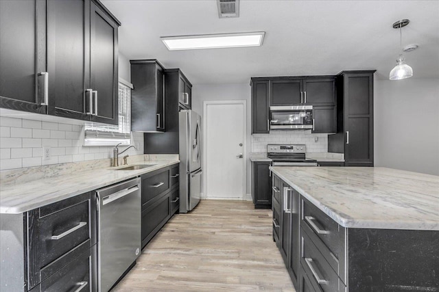 kitchen with light wood finished floors, visible vents, appliances with stainless steel finishes, dark cabinetry, and a sink