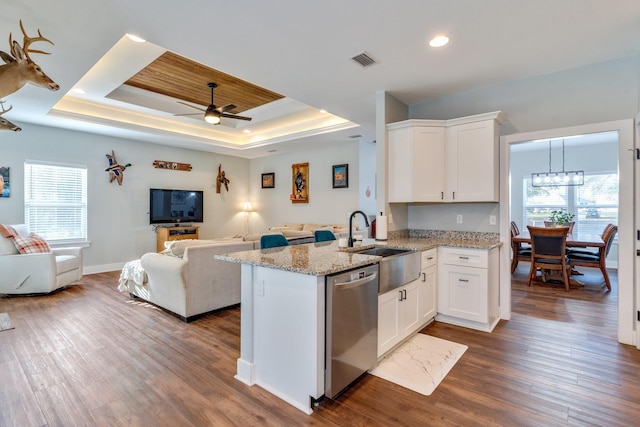 kitchen featuring white cabinets, kitchen peninsula, stainless steel dishwasher, dark hardwood / wood-style flooring, and a tray ceiling