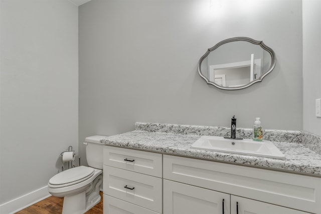 bathroom with toilet, hardwood / wood-style floors, and vanity