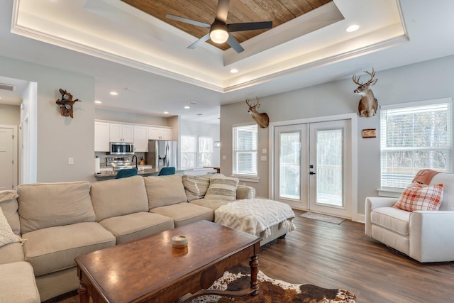 living room featuring ceiling fan, french doors, a tray ceiling, and plenty of natural light