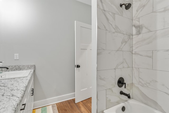 bathroom with tiled shower / bath, wood-type flooring, and vanity