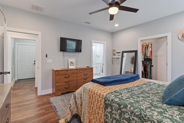 bedroom featuring a closet, ensuite bath, ceiling fan, hardwood / wood-style flooring, and a walk in closet