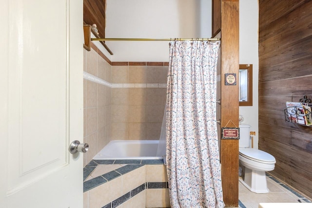 bathroom with wooden walls, tiled shower / bath, and toilet