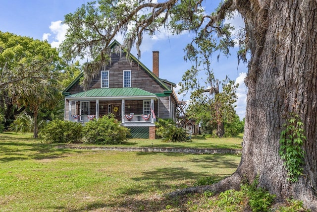 view of front of home with a porch, a front lawn, and a chimney