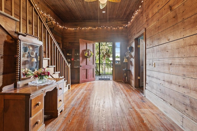 foyer entrance with stairs, wood walls, wood ceiling, and hardwood / wood-style flooring