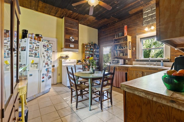 kitchen with a sink, wood walls, plenty of natural light, and white appliances