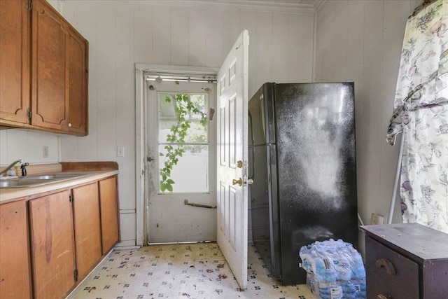 143 Washington Ave, Havana, FL 32333 - kitchen featuring freestanding refrigerator, light floors, brown cabinetry, wood walls, and a sink