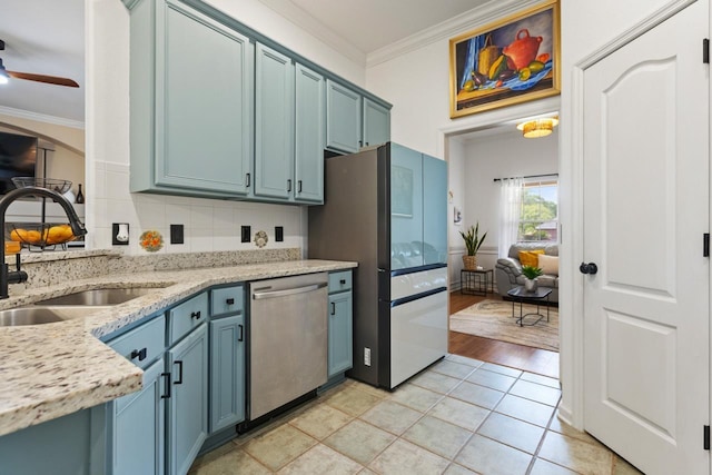 kitchen with stainless steel dishwasher, a sink, ornamental molding, and freestanding refrigerator